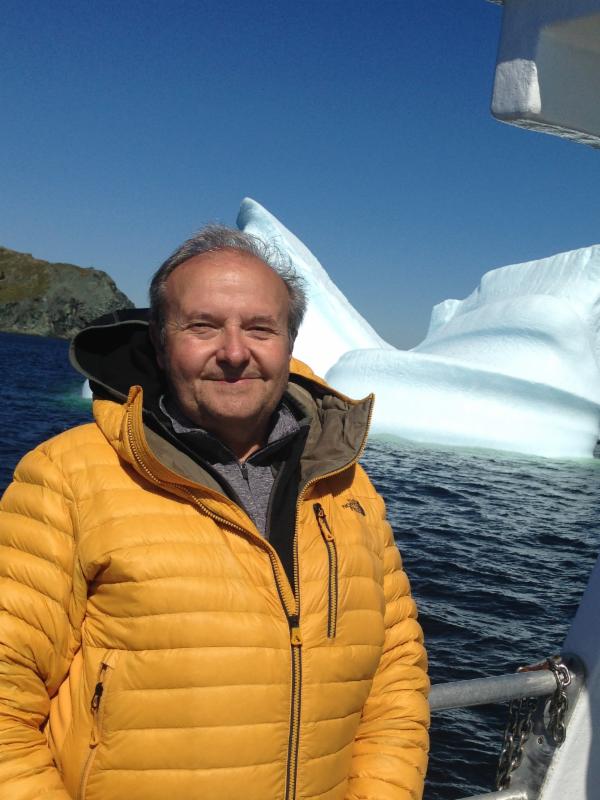 man on a boat with an iceberg in the background