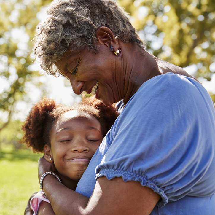 Une grand-mère noire et sa petite-fille se serrent affectueusement dans leurs bras au parc.