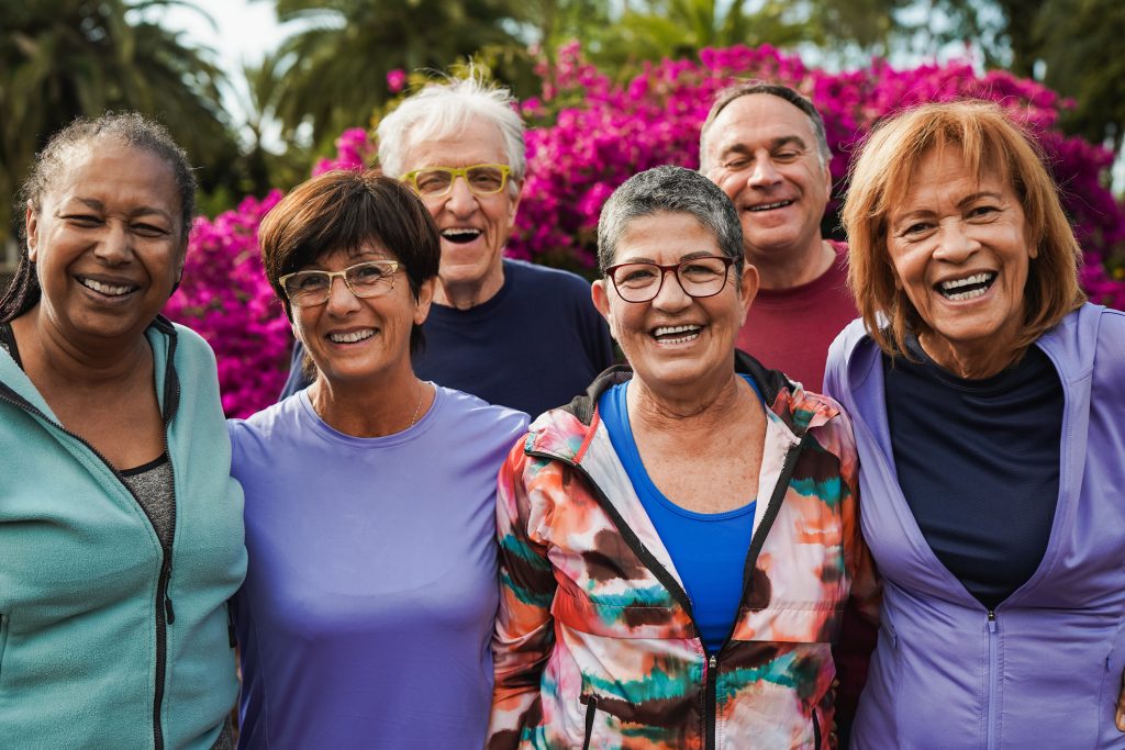A mixed group of older people laughing in a park