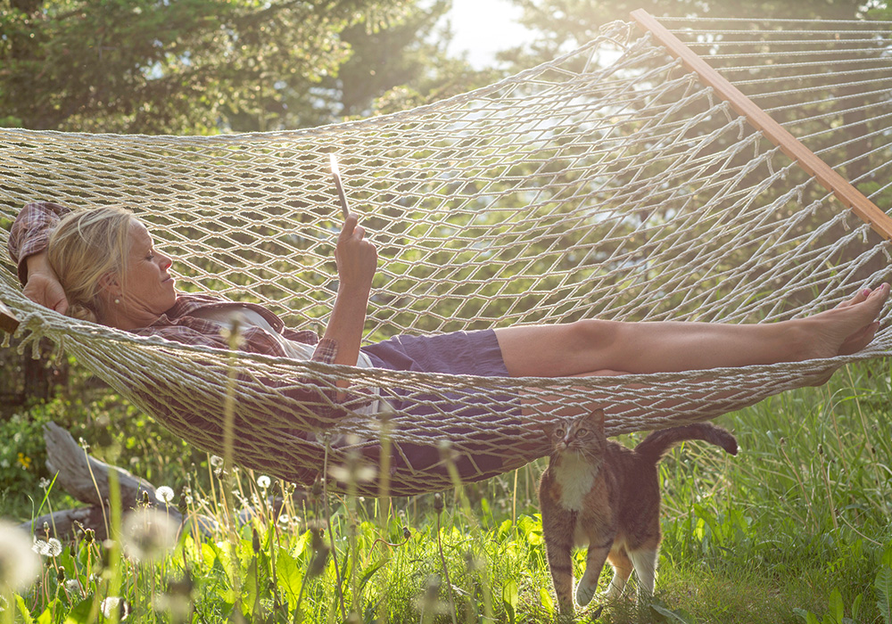 An older woman relaxing outside on a hammock