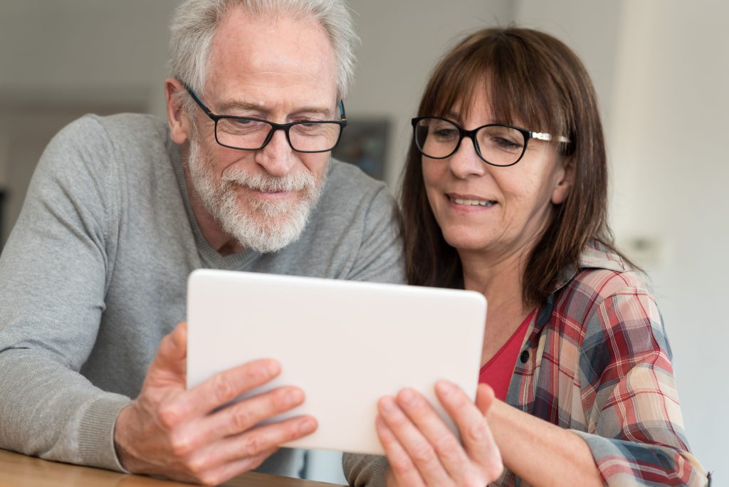 Middle-aged man and woman smiling, using a digital tablet
