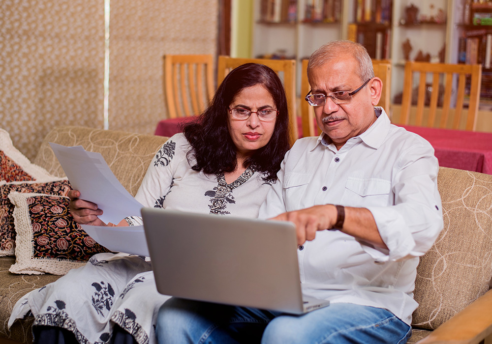 Un homme et une femme âgés, originaires d'Asie du Sud, regardant un écran d'ordinateur.