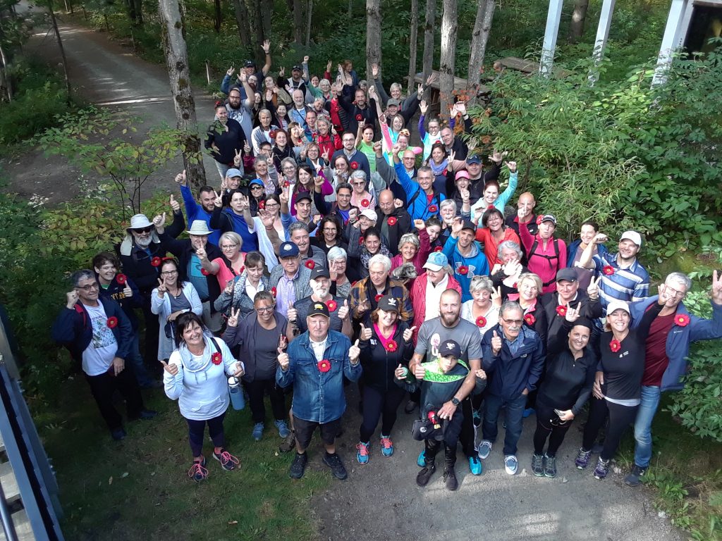Photo d'un groupe de personnes dans une forêt avant un évènement portant l'épingle rouge de Myélome Canada.