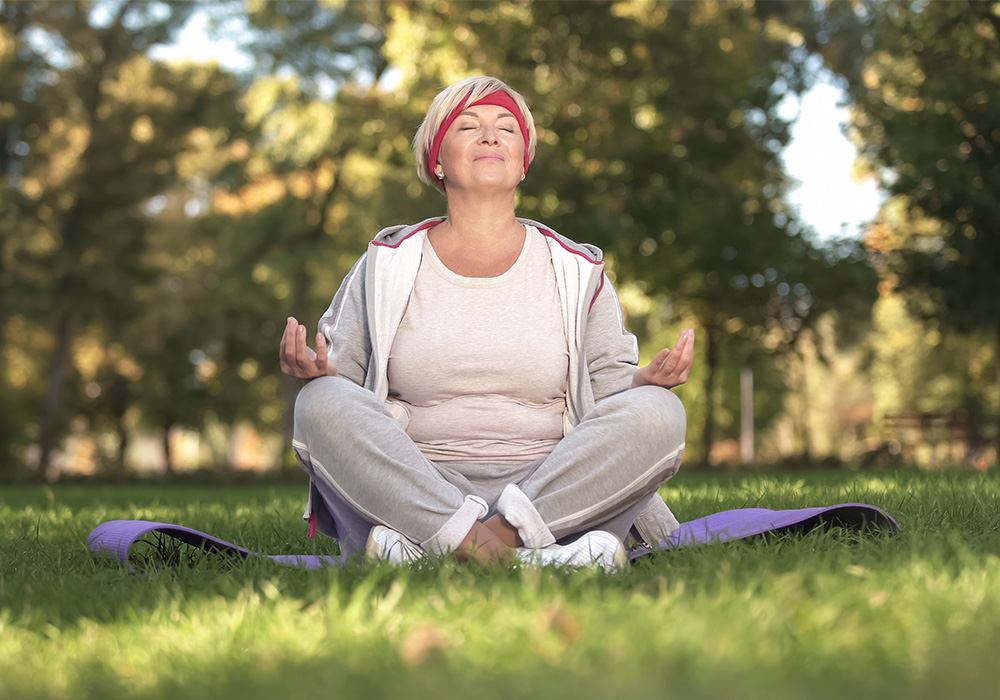 Middle-aged white woman in lotus pose meditating in the park