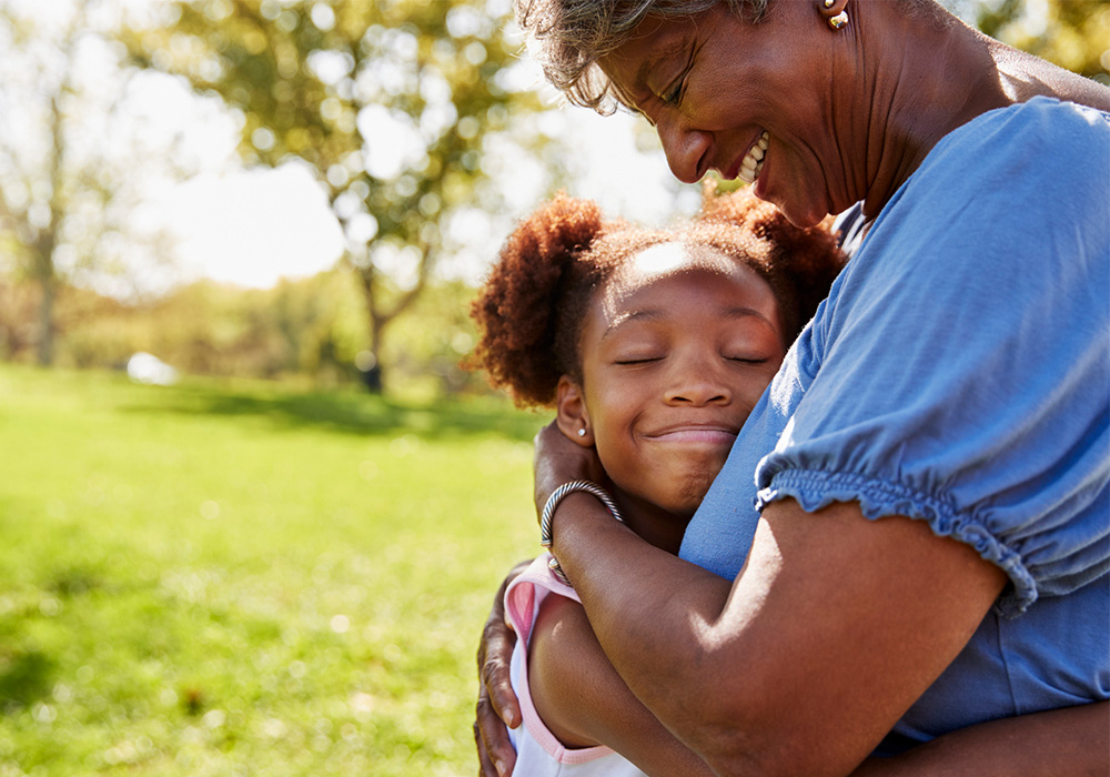 Black grandmother and granddaughter in loving embrace in the park