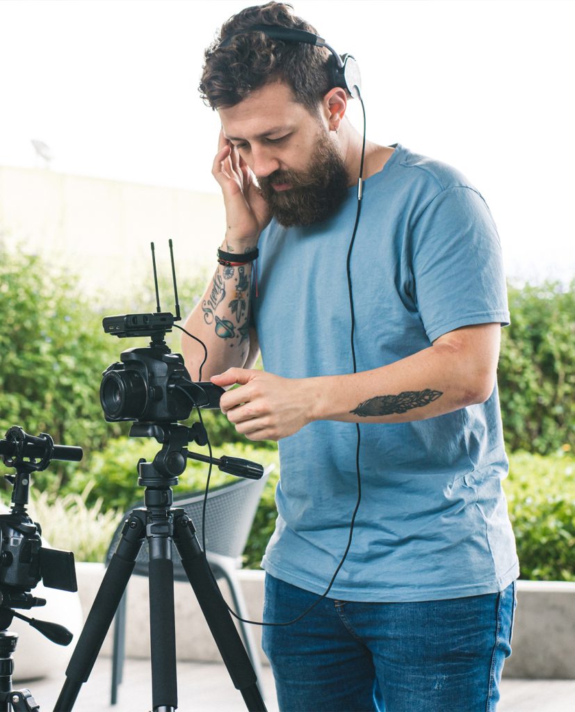 A man wearing headphones and works two cameras.