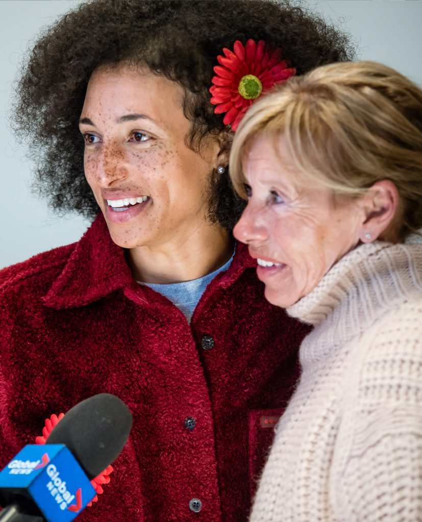 Une jeune femme noire et une femme d'âge moyen portant la fleur de myélome se font interviewer par Global News.