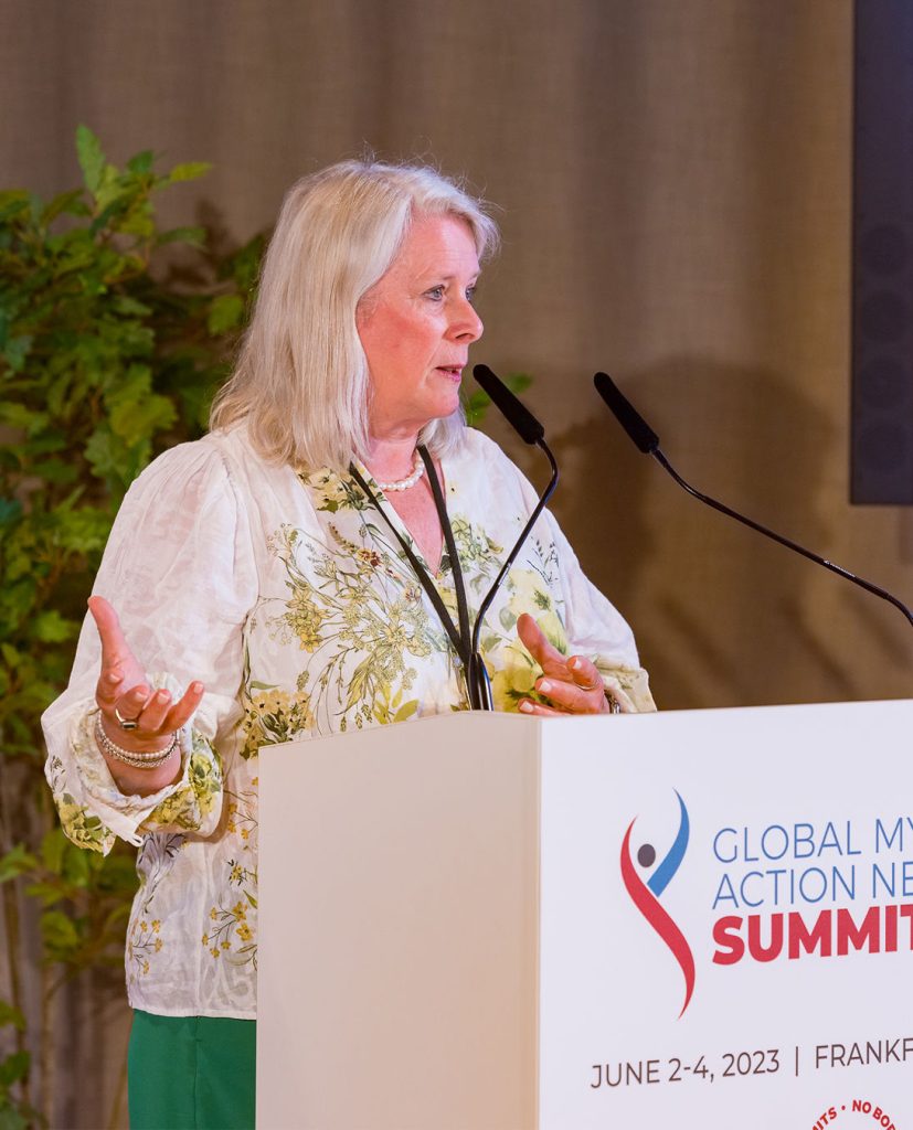 Une femme d'âge moyen prend la parole lors du Sommet du réseau mondial d'action contre le myélome