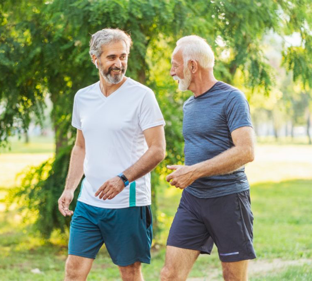 Two grey-haired men in workout clothes walking and talking outside