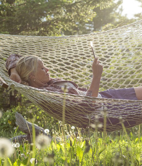 An older woman relaxing outside on a hammock