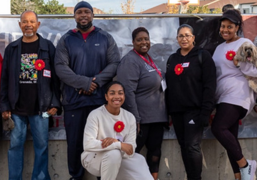 Group of smiling Black people wearing the Myeloma Canada flower pose for the camera at the Multiple Myeloma March in Ontario.