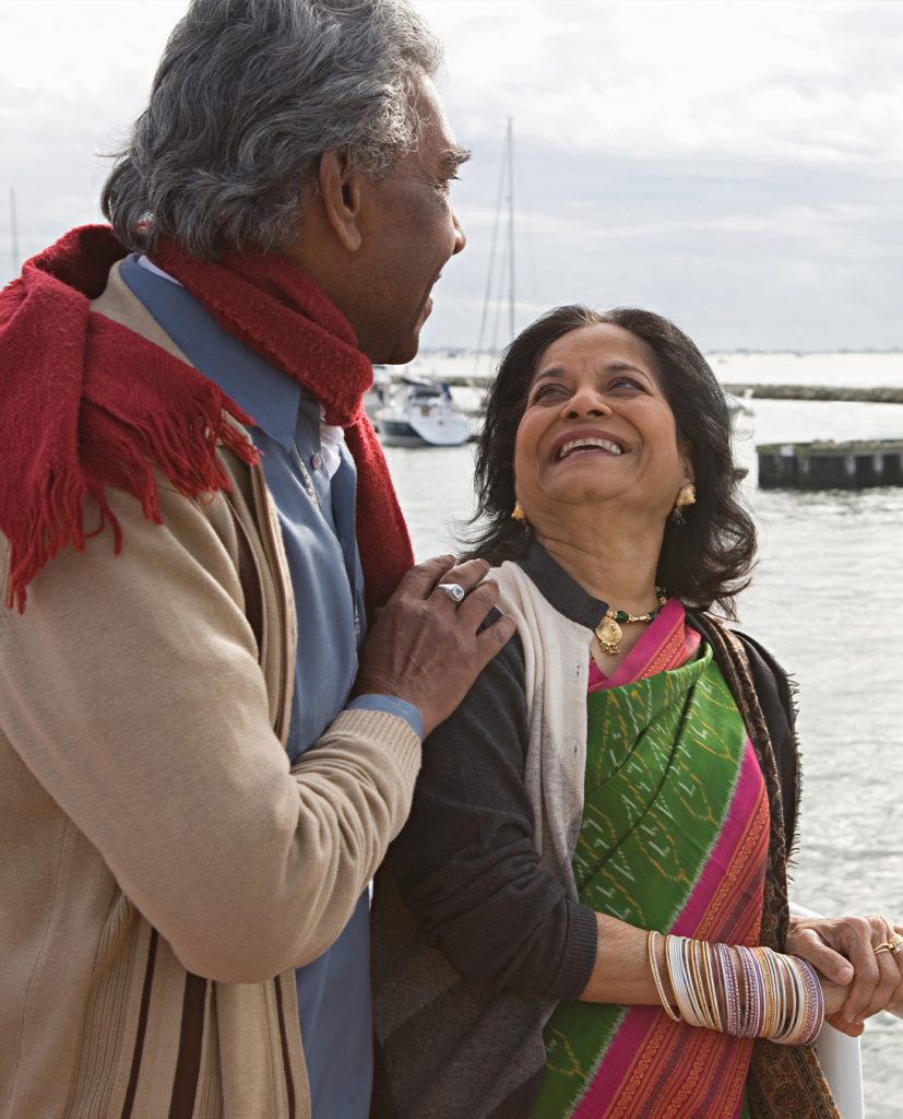 Un homme et une femme originaires de l'Asie du Sud se regardent en souriant sur le bord de l'eau.