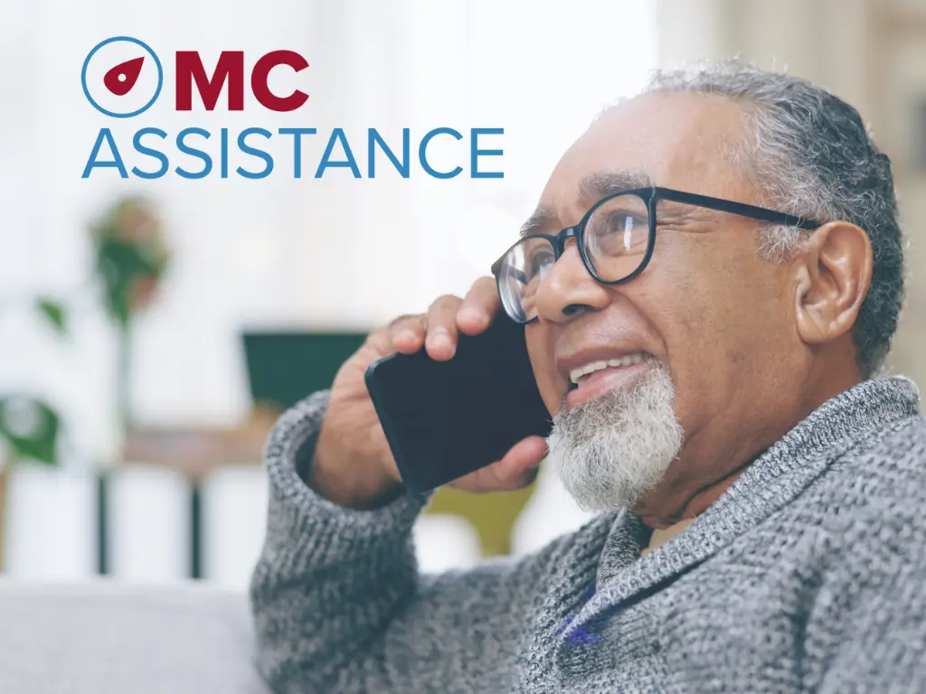An image of a person wearing eyeglasses talking on the phone with Mc Assistance logo on it